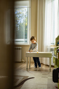 Boy looking through window at home