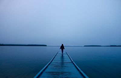 Man standing on pier over sea against clear sky