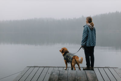 Pretty caucasian girl with brown nova scotia duck tolling retriever staying on wooden pier