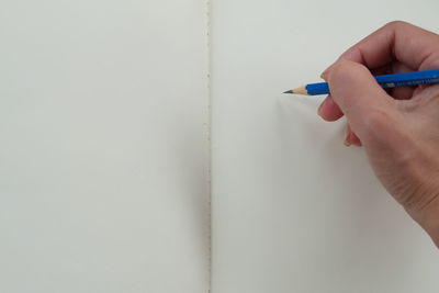 Close-up of person writing on wall with pencil 