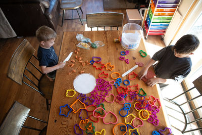 Overhead view of siblings paying with clay and cookie cutters