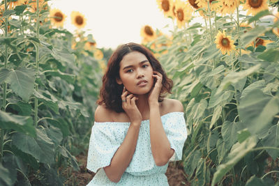 Portrait of woman standing by flowering sunflowers