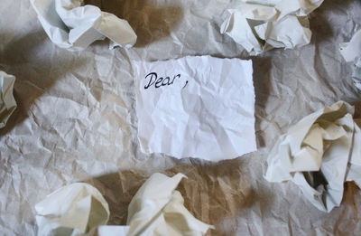 High angle view of dear text by crumpled paper on table