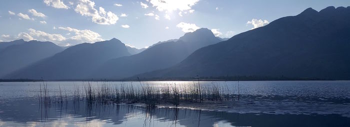 Scenic view of lake by mountains against sky