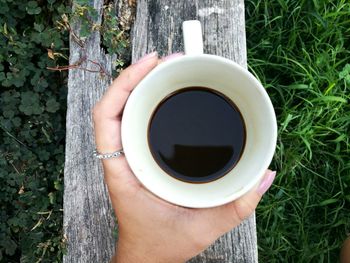 Cropped image of woman holding coffee cup over wood