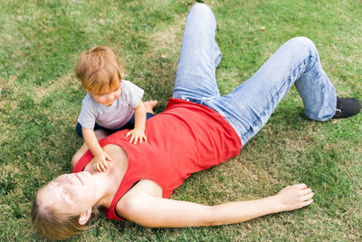 Woman with son sitting on field in yard