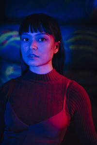 Portrait of illuminated young woman in dark restaurant