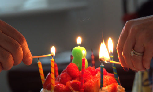 Cropped image of hands lighting birthday candles