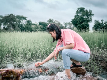 Side view of woman sitting on field