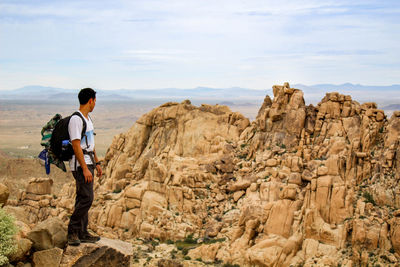 Full length of man standing on rock against sky