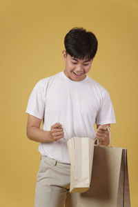 Portrait of a smiling young man standing against yellow background