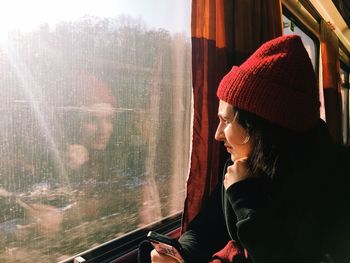 Young woman wearing knit hat sitting in train