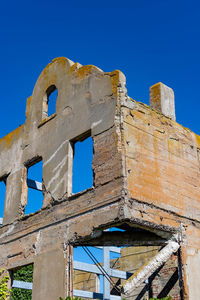 Low angle view of old ruins against clear blue sky