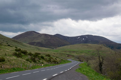 Road leading towards mountains against sky