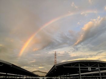Low angle view of rainbow over building against sky
