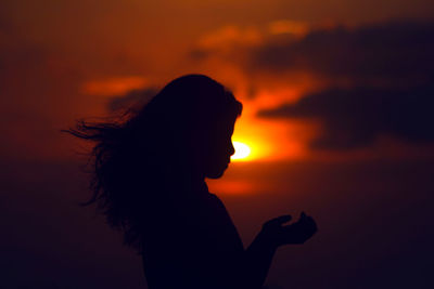 Silhouette woman against orange sky during sunset