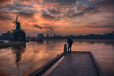 Man standing on pier against sky during sunset