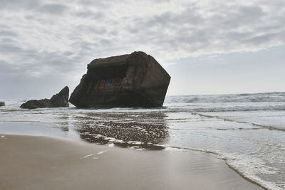 Rock formation on beach against sky