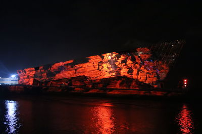 River by illuminated city against sky at night