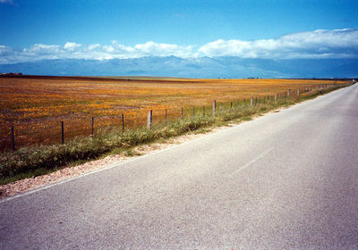 Country road against cloudy sky