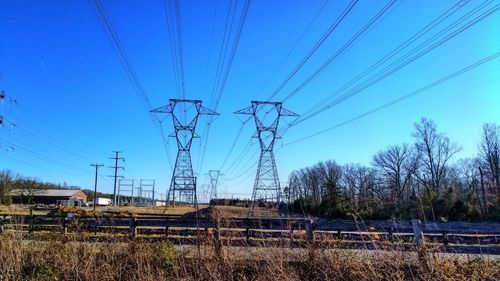 Low angle view of electricity pylon against blue sky