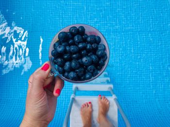 High angle view of woman holding blueberries over the pool