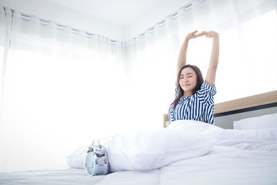 Young woman sitting on bed at home