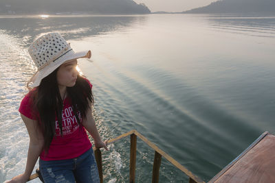 Woman wearing hat standing by sea