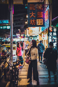Rear view of people walking on illuminated street