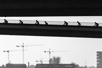 Silhouette people on bridge against clear sky