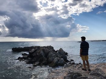 Rear view of man standing on beach against sky