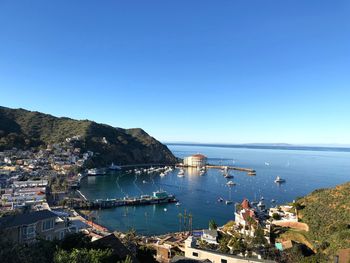 High angle view of city by sea against clear blue sky