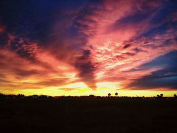 Silhouette landscape against dramatic sky during sunset