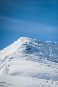 Aerial view of snowcapped mountain against blue sky