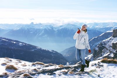 Woman standing on snowcapped mountain against sky