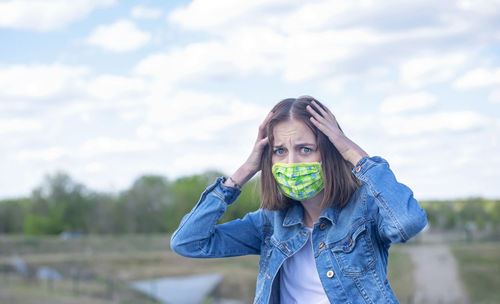 Portrait of young woman standing on field against sky