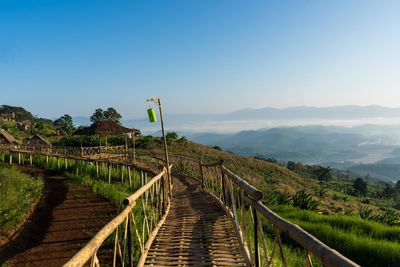 Panoramic shot of footpath leading towards mountains against clear blue sky