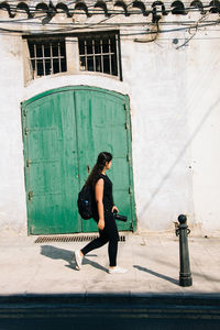 Side view of young woman standing against built structure