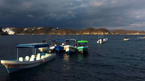 Boats on lake against cloudy sky