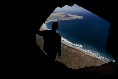 Silhouette of a man from cave on the famara cliff in lanzarote, spain