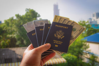 Cropped hand holding passports and paper currency in city