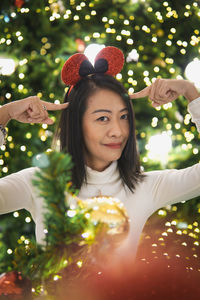 Portrait of young woman with christmas tree at night