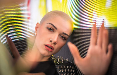 Portrait of young woman with shaved head standing against abstract backgrounds