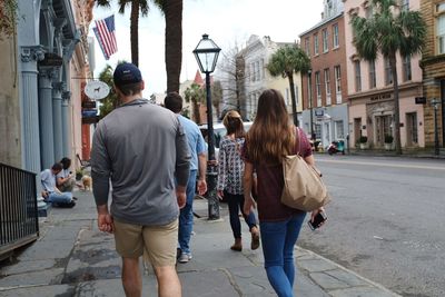 Rear view of people walking on street in city