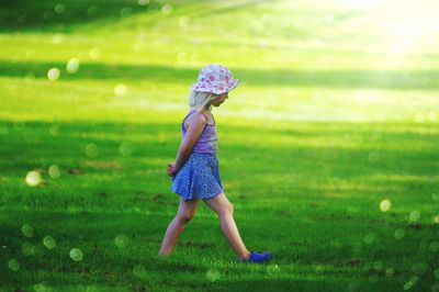 Side view of girl walking on grassy field at park