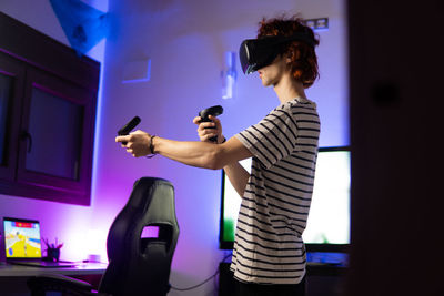 Young man wearing virtual reality simulator playing game at home