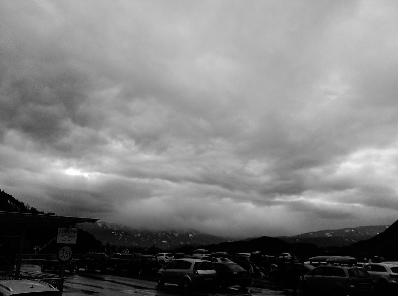 sky, transportation, car, cloud - sky, land vehicle, building exterior, architecture, built structure, mode of transport, cloudy, city, mountain, overcast, road, cityscape, weather, cloud, street, outdoors, storm cloud