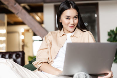 Portrait of young woman using laptop at home