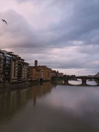 Buildings by river against sky in city