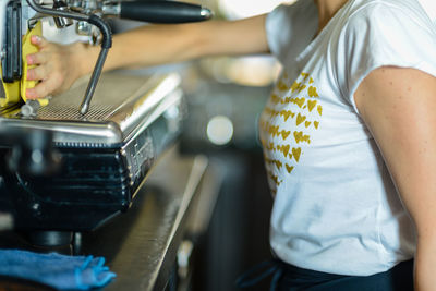 Young female barista cleaning espresso italian coffee maker, se